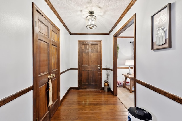 hallway with a notable chandelier, wood finished floors, ornamental molding, and a textured ceiling