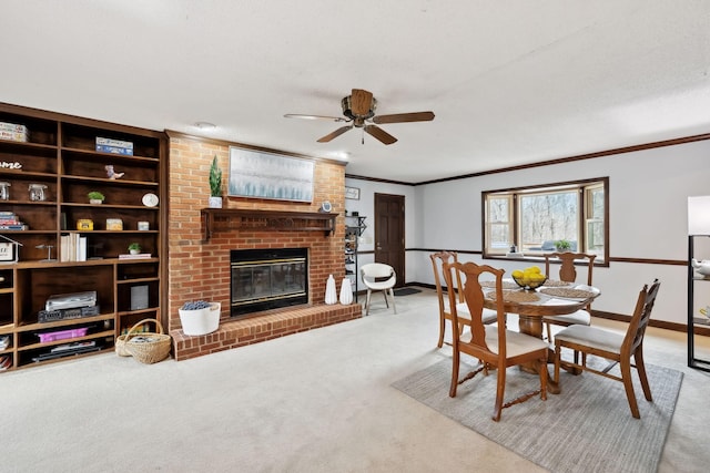 dining space with crown molding, baseboards, carpet floors, ceiling fan, and a fireplace