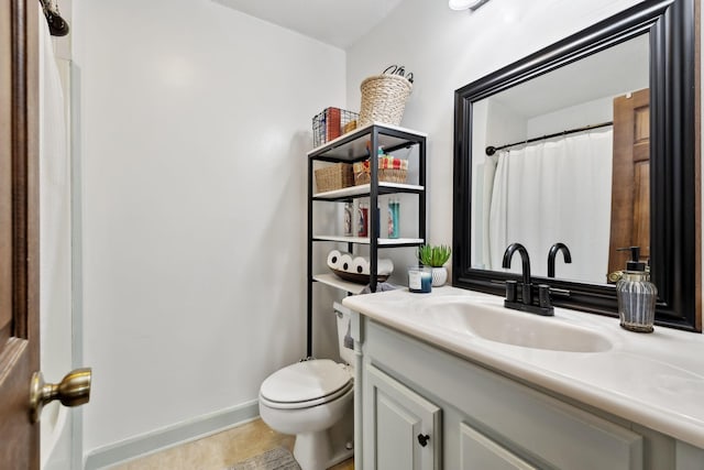bathroom featuring baseboards, toilet, and vanity