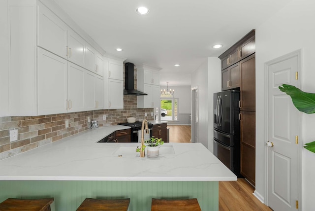 6525 Chessington Dr, Nashville, TN 37221 - kitchen featuring decorative backsplash, a peninsula, fridge with ice dispenser, gas range, and wall chimney range hood