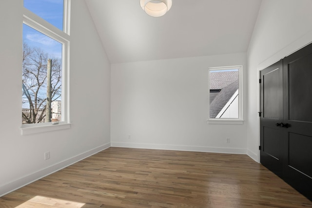 interior space with baseboards, lofted ceiling, and wood finished floors