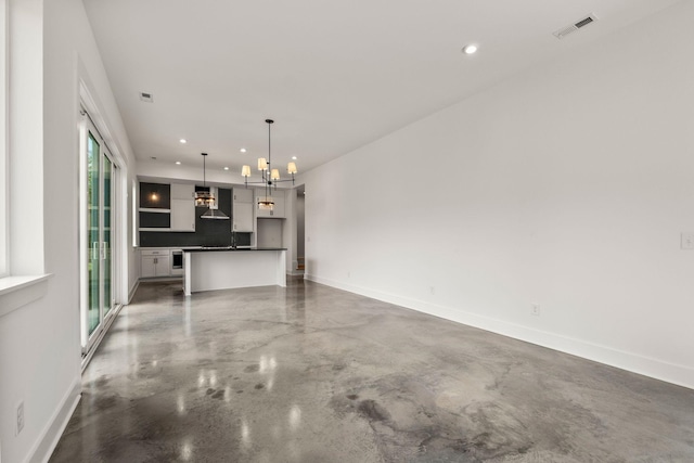 unfurnished living room with baseboards, visible vents, concrete floors, and recessed lighting