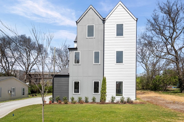 view of front of house featuring a front lawn, driveway, and board and batten siding