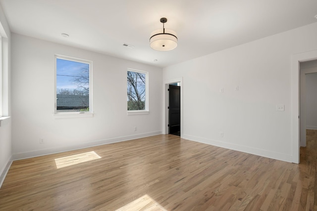 unfurnished room featuring baseboards, light wood-style floors, and visible vents
