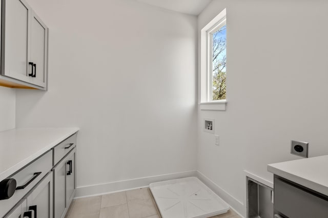 clothes washing area featuring electric dryer hookup, light tile patterned floors, baseboards, cabinet space, and hookup for a washing machine