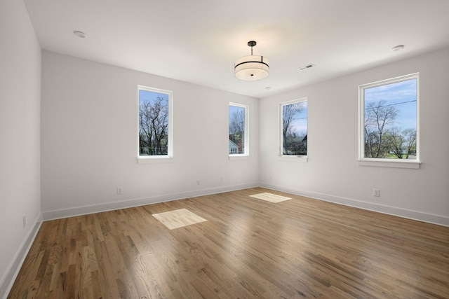 spare room with visible vents, baseboards, and wood finished floors