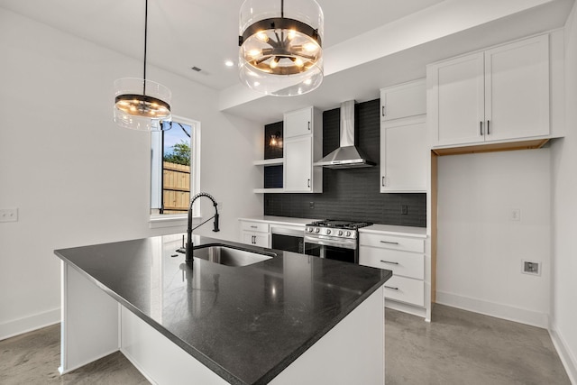 kitchen with tasteful backsplash, gas stove, white cabinetry, a sink, and wall chimney range hood