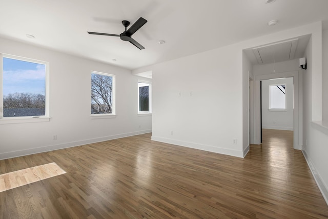 unfurnished room with attic access, baseboards, wood finished floors, and a ceiling fan