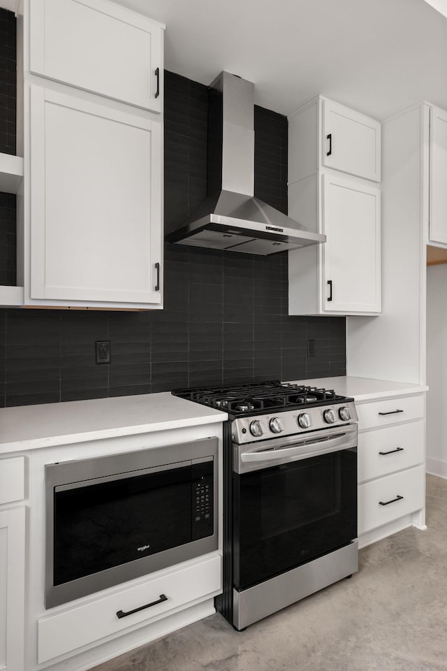 kitchen featuring light countertops, stainless steel range with gas stovetop, backsplash, built in microwave, and wall chimney range hood