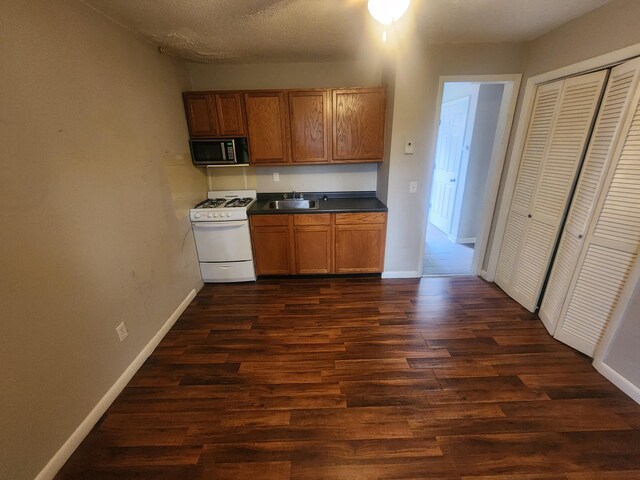 906 Edwards St, Madisonville, KY 42431 - kitchen featuring a sink, stainless steel microwave, dark countertops, white gas stove, and dark wood-type flooring
