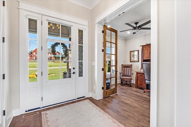 entryway with visible vents, baseboards, ornamental molding, wood finished floors, and a ceiling fan