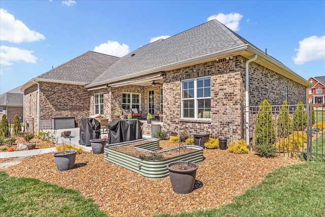 rear view of house with brick siding, fence, ceiling fan, and a shingled roof