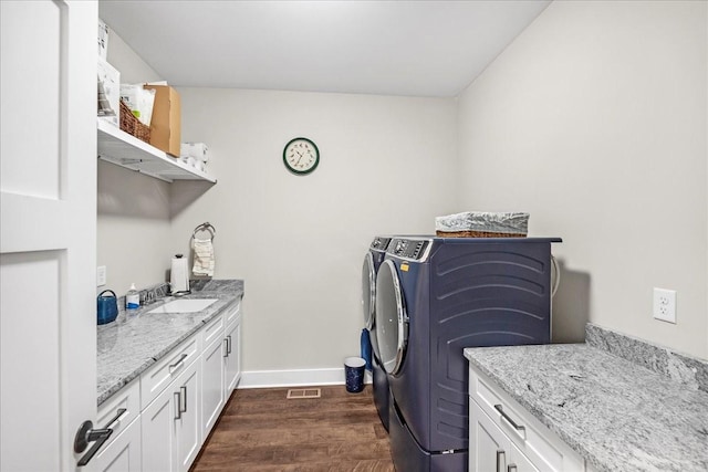 laundry room with dark wood-style floors, cabinet space, independent washer and dryer, visible vents, and baseboards