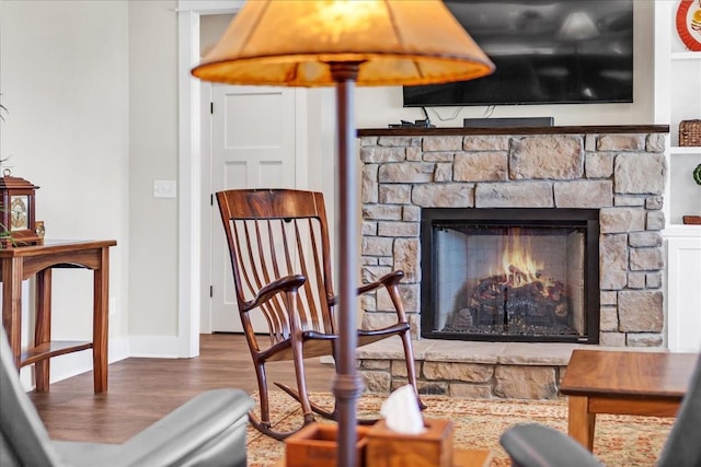 living area featuring a fireplace, wood finished floors, and baseboards
