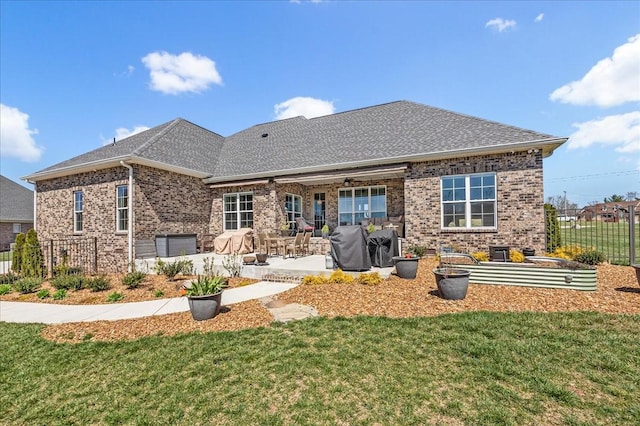 back of house with brick siding, fence, a patio area, and a lawn