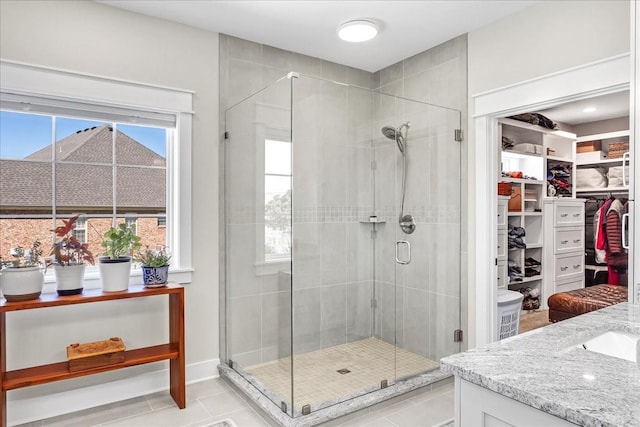 full bathroom with a stall shower, tile patterned flooring, vanity, and a spacious closet