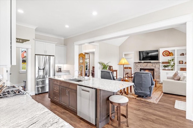 kitchen featuring a kitchen breakfast bar, stainless steel appliances, dark wood-style floors, and a sink