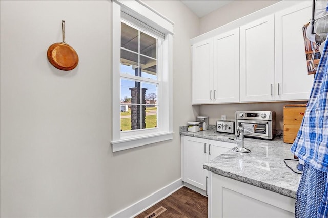 interior space with a toaster, dark wood-type flooring, visible vents, and baseboards