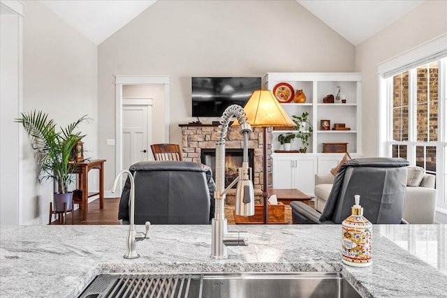 living area with high vaulted ceiling, wood finished floors, and a fireplace