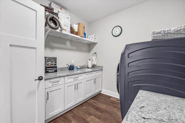 clothes washing area with a sink, visible vents, cabinet space, and dark wood-type flooring