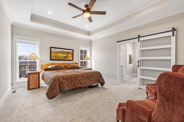 bedroom with light colored carpet, a raised ceiling, a barn door, and baseboards