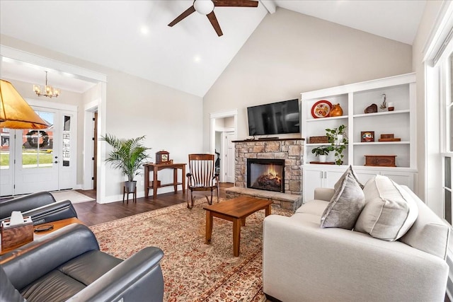 living area with plenty of natural light, high vaulted ceiling, a stone fireplace, and ceiling fan with notable chandelier