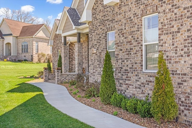 view of side of property featuring brick siding and a lawn