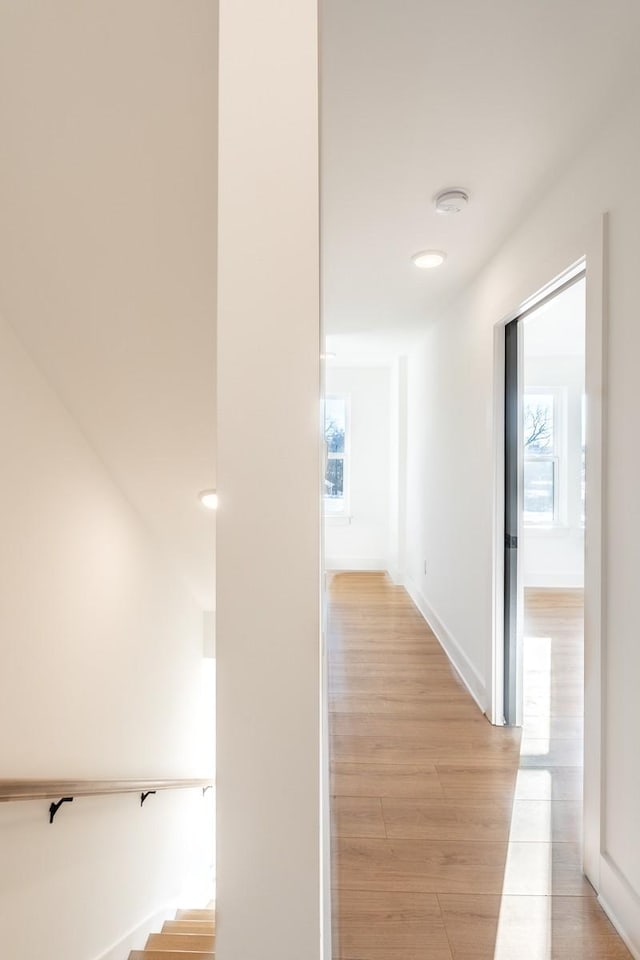 hall featuring recessed lighting, baseboards, light wood finished floors, and a wealth of natural light