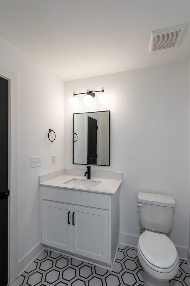 bathroom featuring vanity, toilet, tile patterned floors, baseboards, and visible vents