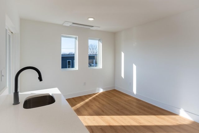 interior space featuring visible vents, wood finished floors, baseboards, light countertops, and a sink