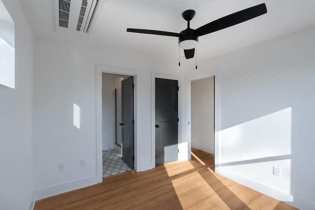 unfurnished bedroom with visible vents, arched walkways, wood finished floors, baseboards, and ensuite bathroom