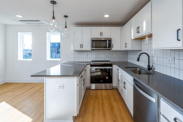 kitchen featuring a sink, decorative backsplash, appliances with stainless steel finishes, and a peninsula