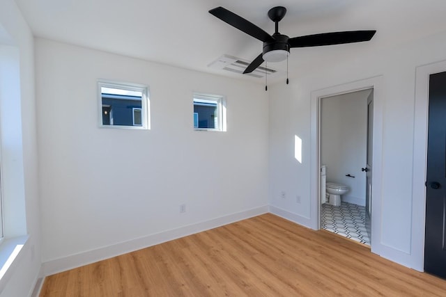 unfurnished bedroom with baseboards, a ceiling fan, light wood-type flooring, and ensuite bath
