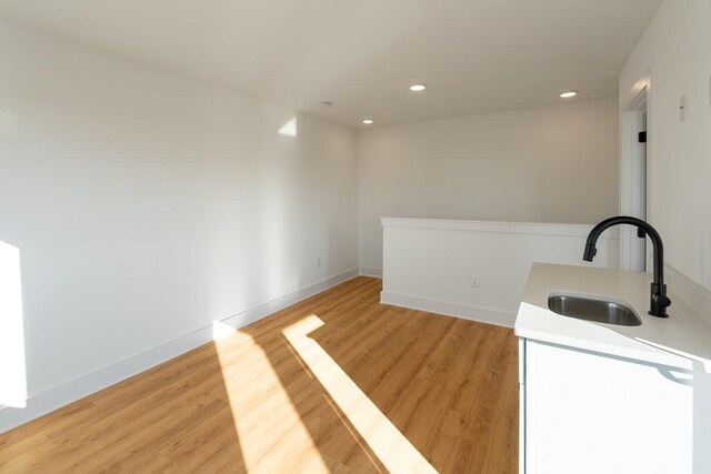 bar with a sink, recessed lighting, baseboards, and light wood-type flooring