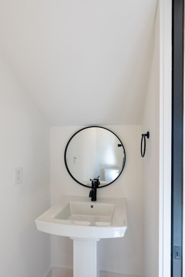 bathroom featuring baseboards, vaulted ceiling, and a sink