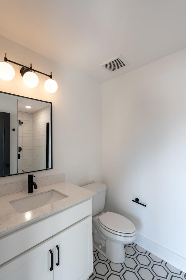 full bath featuring vanity, toilet, tiled shower, and visible vents
