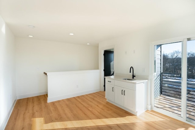 bar featuring recessed lighting, baseboards, a sink, and light wood-type flooring