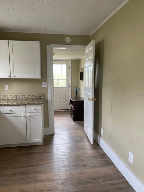 kitchen with crown molding, white cabinets, light stone countertops, and dark wood-style flooring