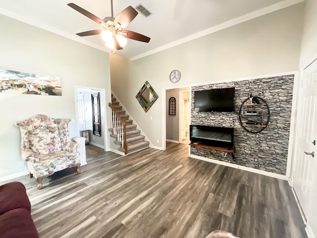 living room with visible vents, wood finished floors, baseboards, a stone fireplace, and stairway