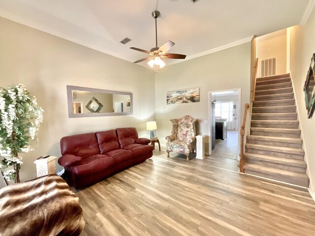 living room with visible vents, ornamental molding, stairs, and ceiling fan