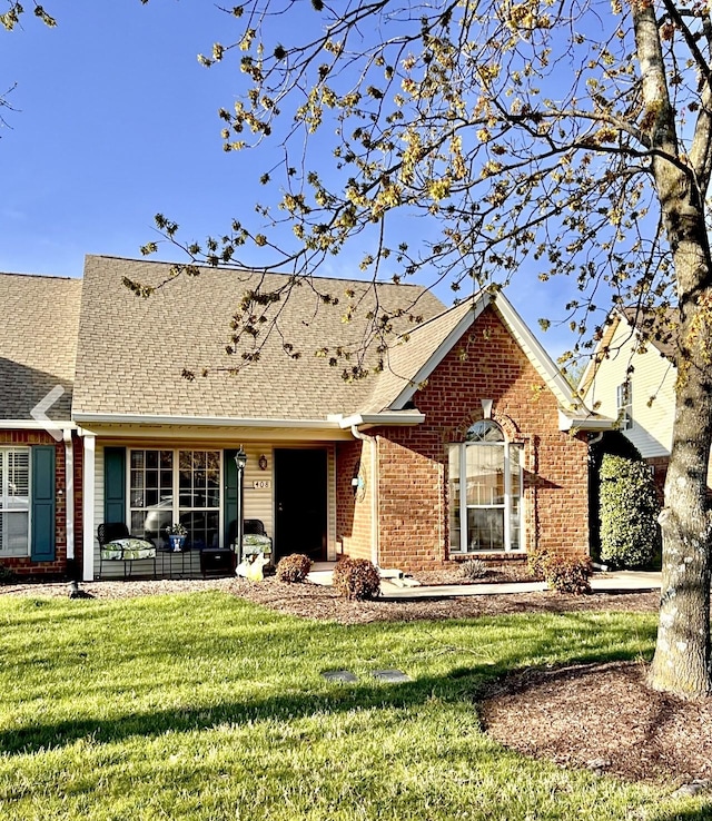 ranch-style house featuring roof with shingles, a front lawn, and brick siding