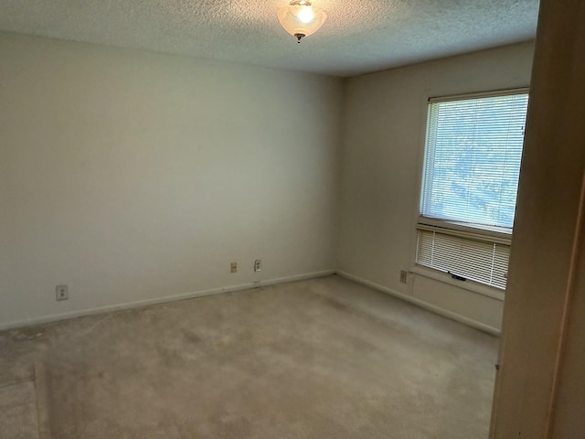 carpeted empty room featuring a textured ceiling and baseboards