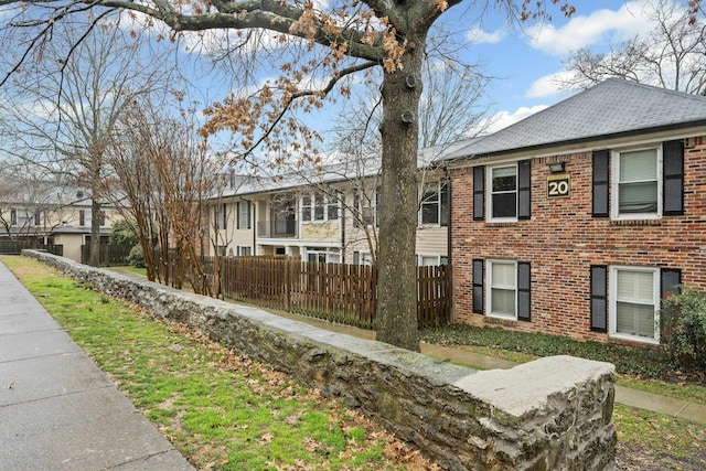 5025 Hillsboro Pike Unit 20E, Nashville, TN 37215 - view of property exterior featuring a shingled roof, fence, brick siding, and a residential view