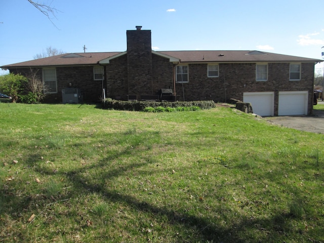back of property featuring a chimney, central AC unit, brick siding, and a yard