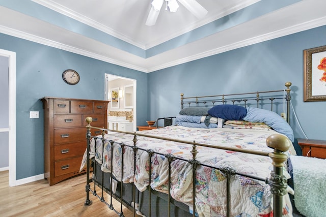 bedroom with crown molding, a raised ceiling, wood finished floors, ensuite bathroom, and baseboards