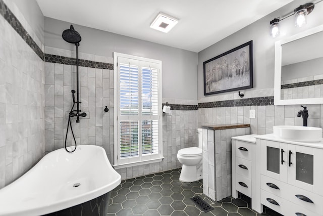 full bathroom with tile walls, a soaking tub, toilet, tile patterned floors, and vanity