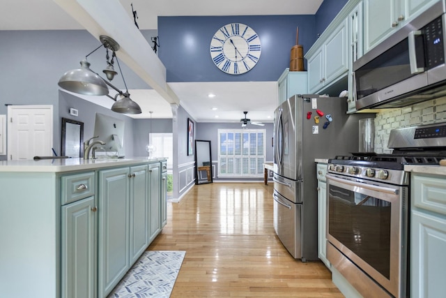 kitchen with a ceiling fan, stainless steel appliances, light countertops, and light wood-type flooring