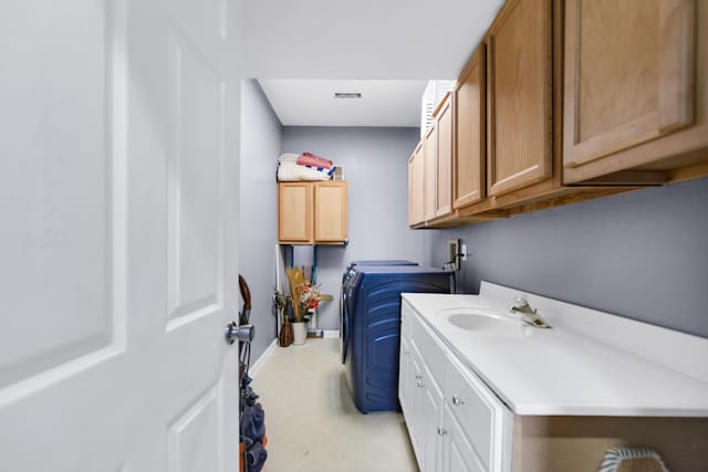 washroom with a sink, cabinet space, washing machine and dryer, and baseboards