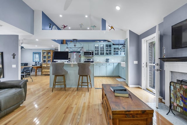 kitchen featuring a center island, light wood-type flooring, ceiling fan, stainless steel appliances, and decorative backsplash