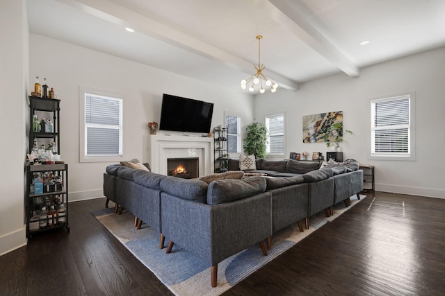 living area featuring a notable chandelier, beam ceiling, a fireplace, dark wood finished floors, and baseboards